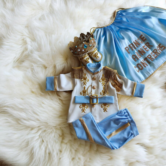 baby boy wearing blue gold baby boy birthday outfit luxury prince suit prince outfit with cape and crown birthday photoshoot