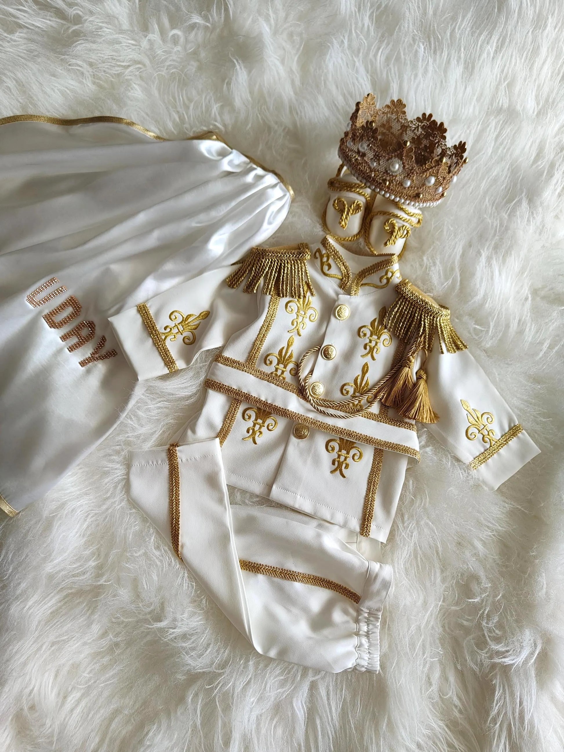 baby boy wearing nan prince outfit with cape and crown birthday photoshoot