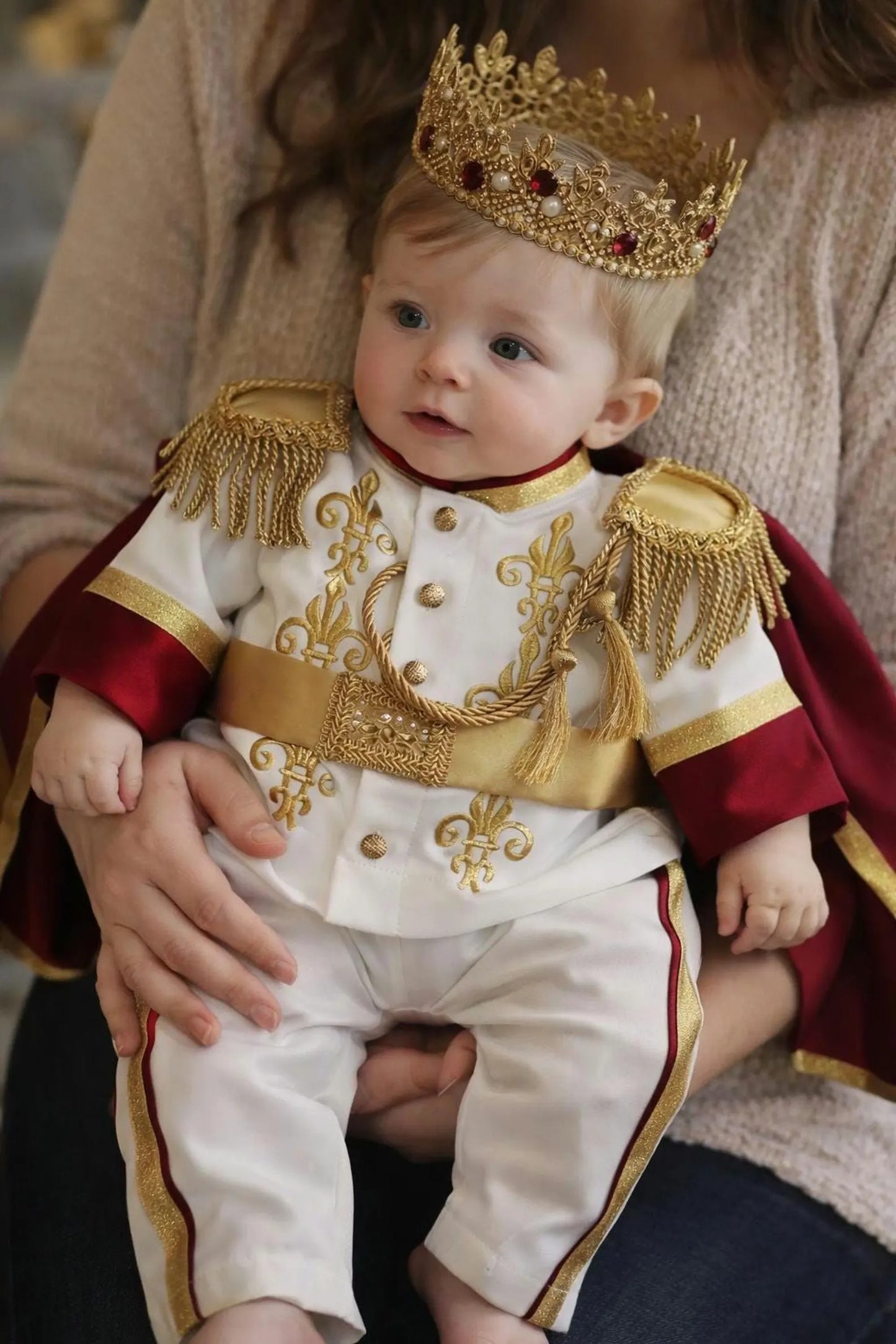 baby boy wearing nan prince outfit with cape and crown birthday photoshoot