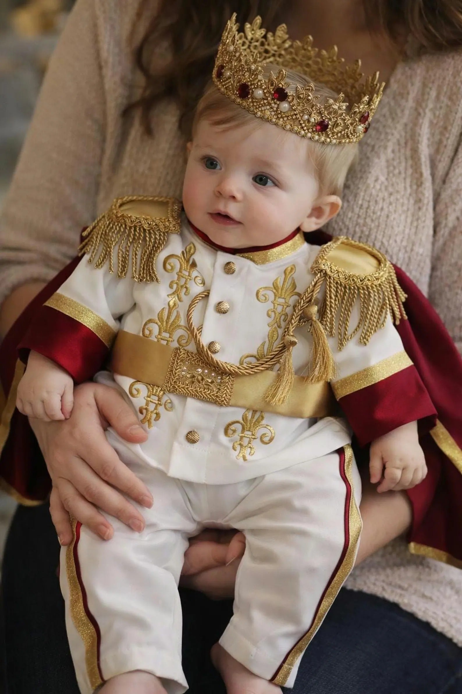 baby boy wearing nan prince outfit with cape and crown birthday photoshoot