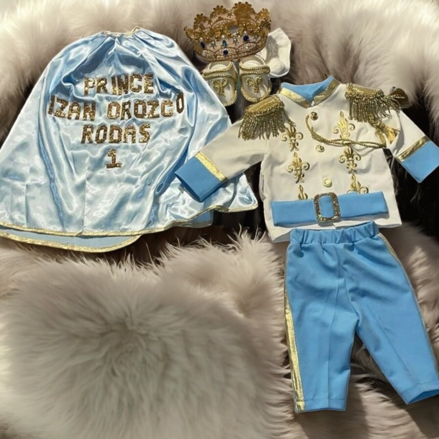 baby boy wearing nan prince outfit with cape and crown birthday photoshoot